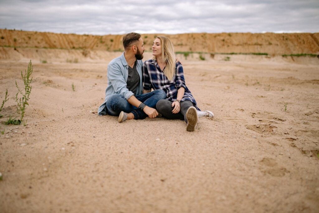 couple sitting on sand in desert