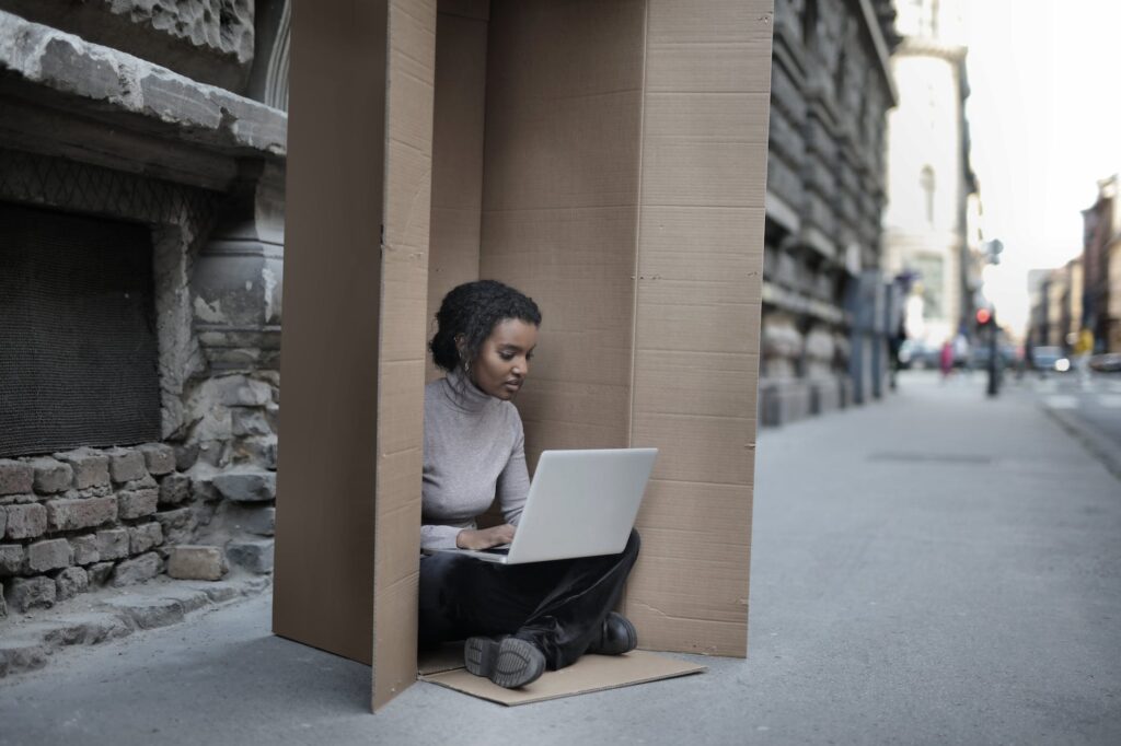 african american female sitting inside cardboard box with laptop