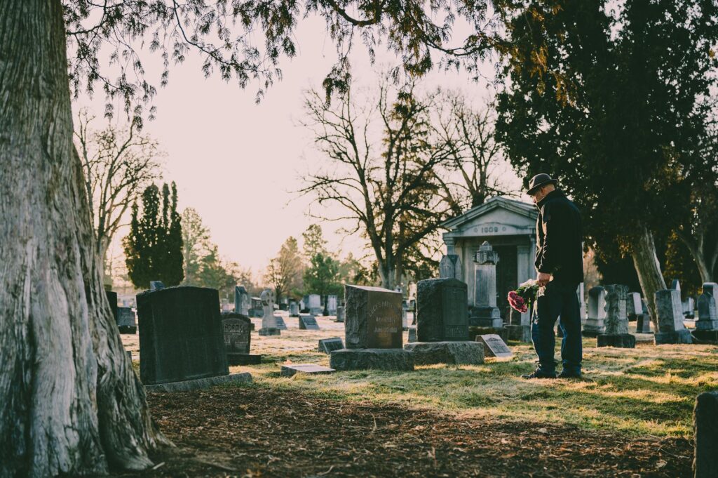 man in black jacket standing in front of grave