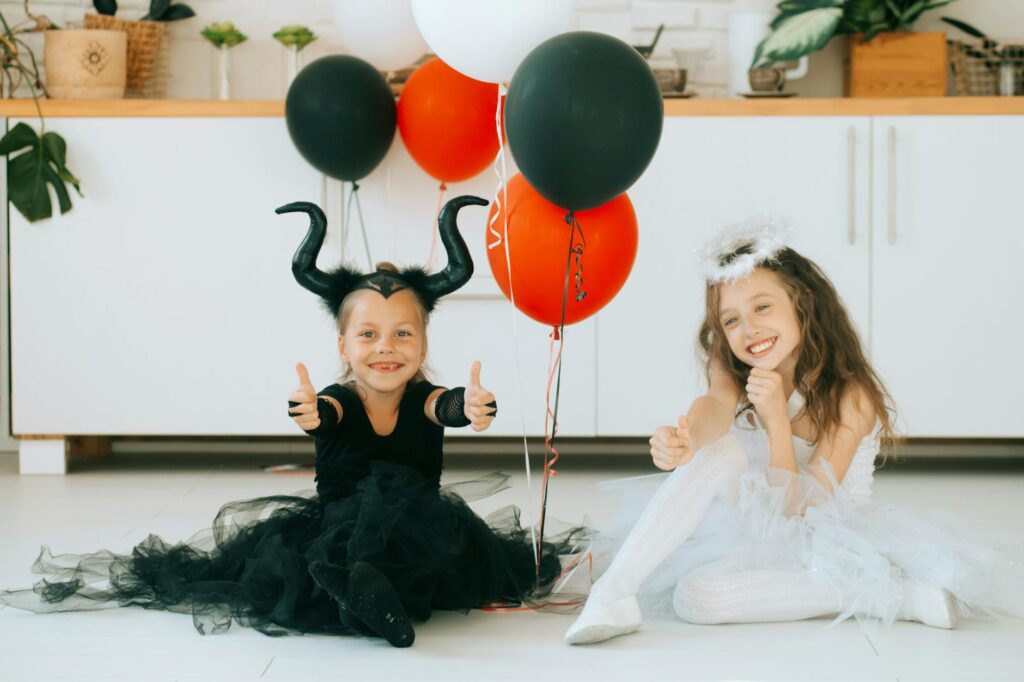 two cute girls in halloween costume sitting on the floor